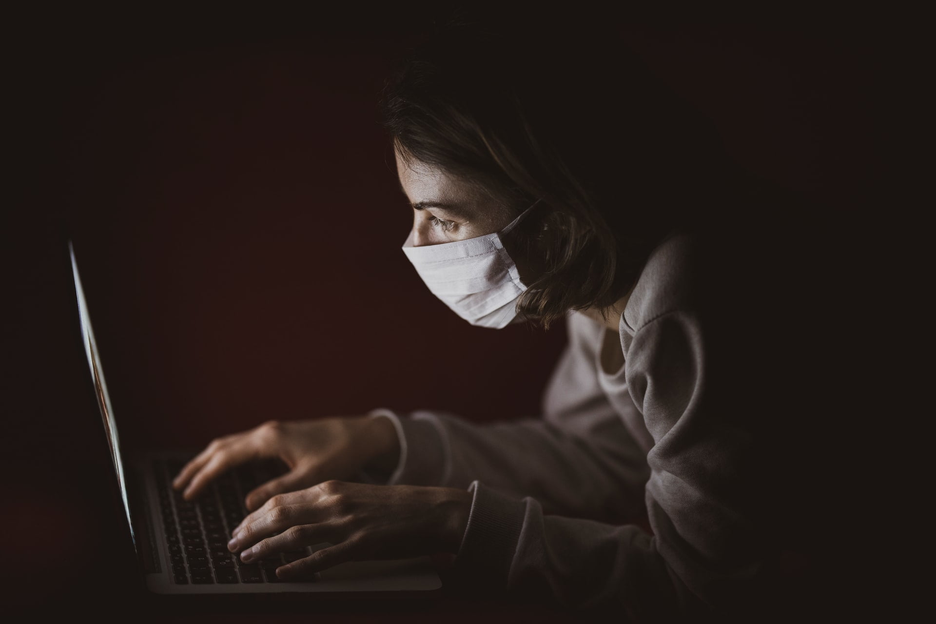 a man with a mask on his face using a laptop