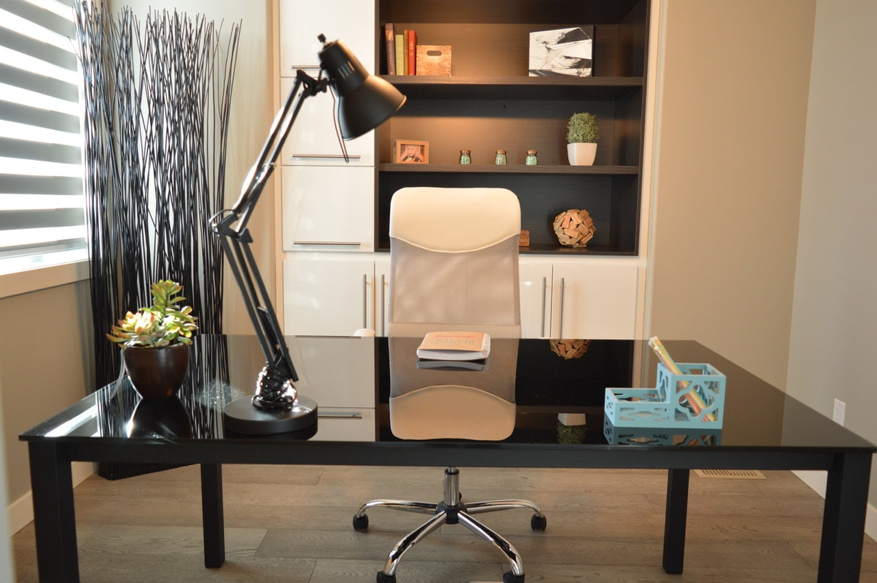 a desk with a lamp and a bookcase