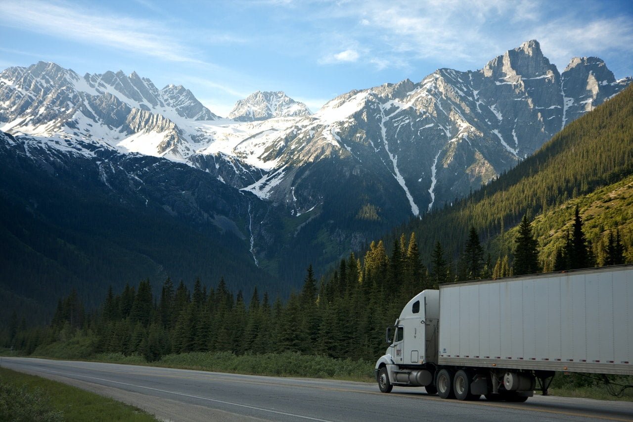 a semi truck on a road with mountains in the background