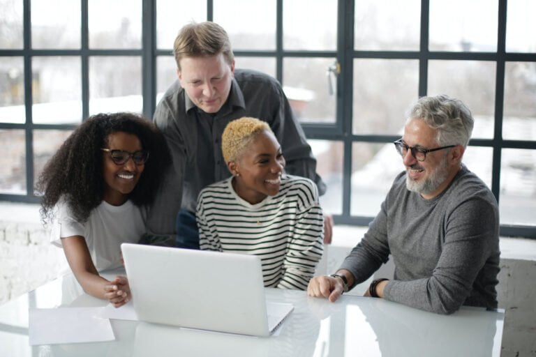 a group of people sitting around a table looking at a laptop