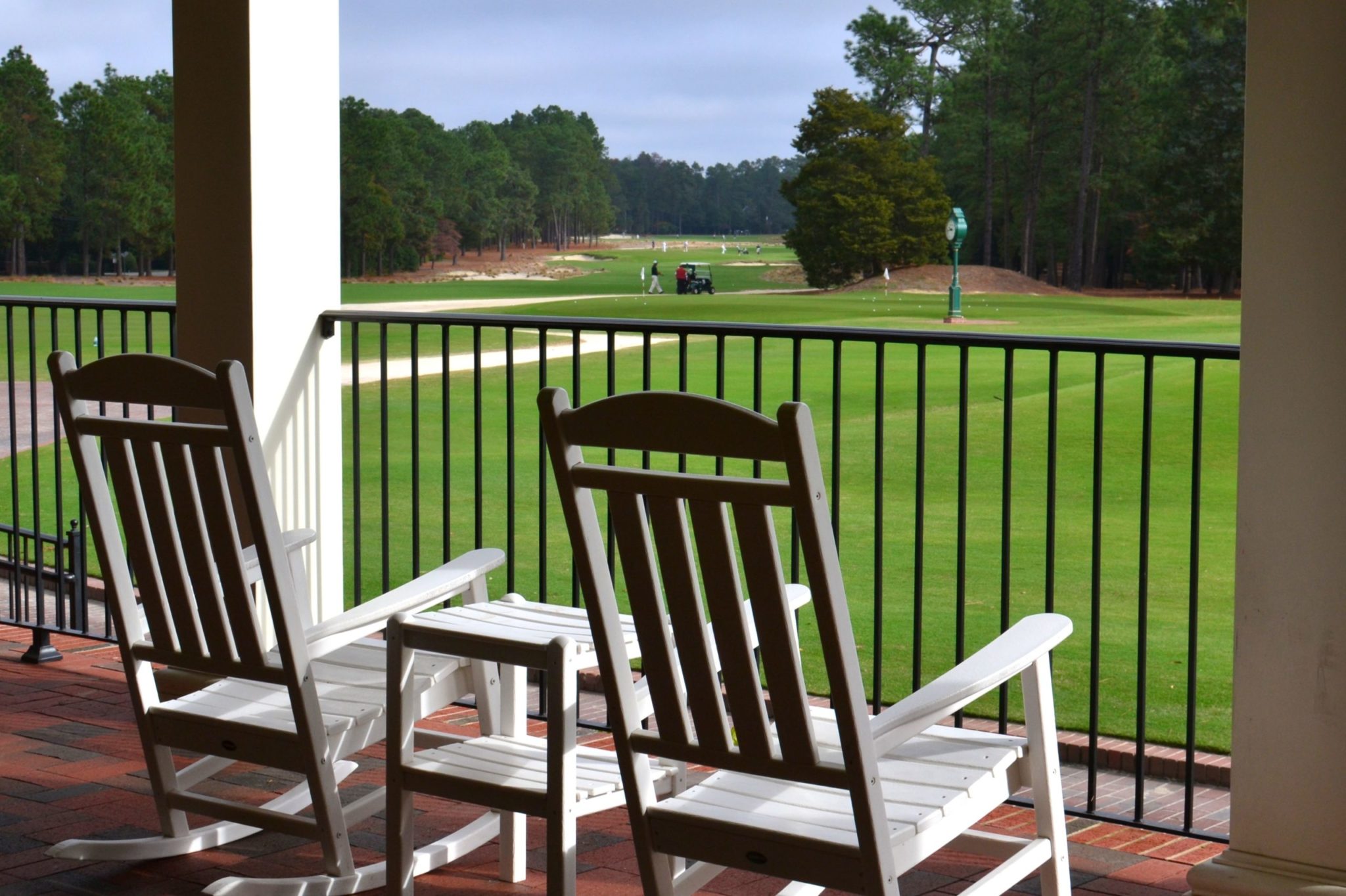 a deck with chairs and a view of a grassy field and trees